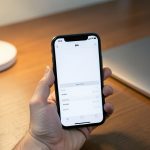 Smartfon na biurku z aplikacją bankową, obok laptop i lampka biurkowa